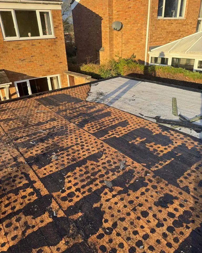 Extension flat roof stripped of old felt, showing the timber deck and old bitumen