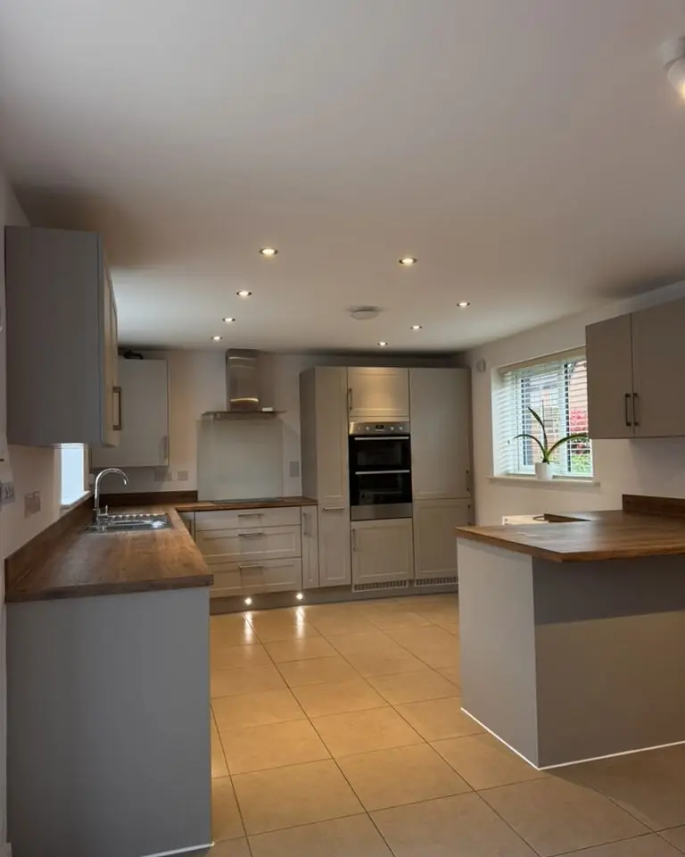 Residential shaker kitchen with oak worktops, double oven and tiled floor