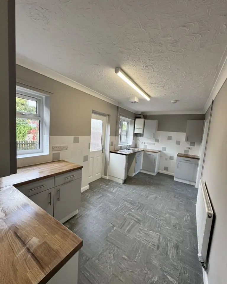 New social housing kitchen with grey units, oak-effect worktops and vinyl flooring, Peterborough